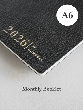 Minimalist black A6 monthly booklet cover featuring crisp white typography displaying the title "2026" for year planning.