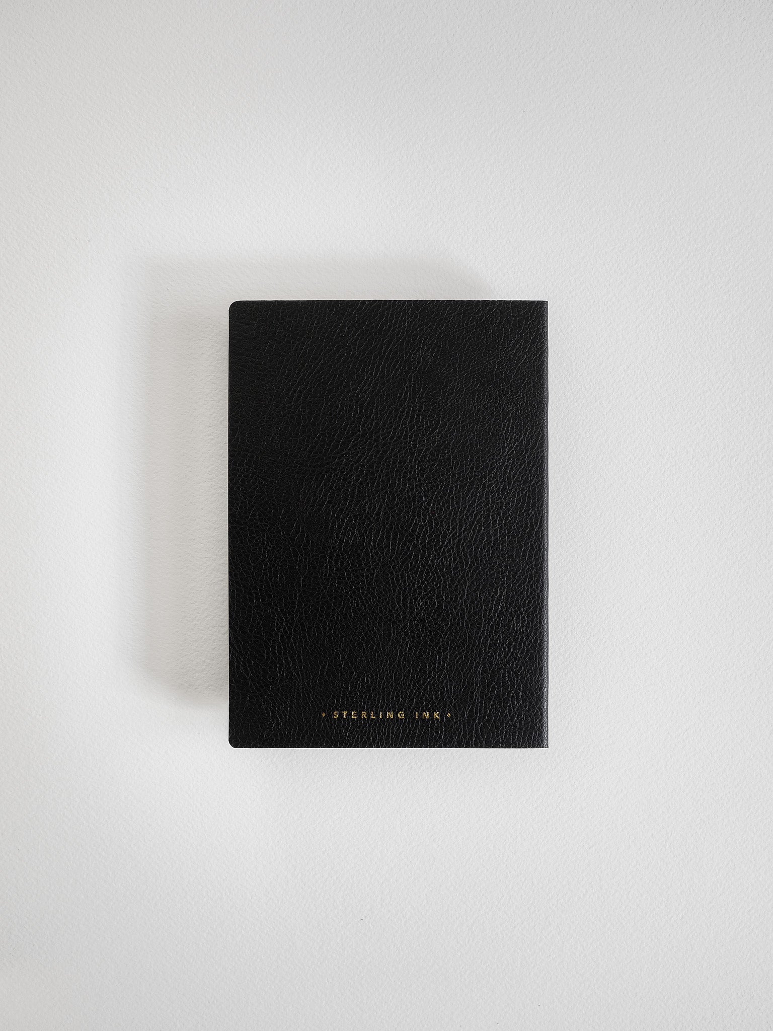 Sleek black A6 notebook featuring a sophisticated, textured faux leather cover and discreet metallic "Sterling Ink" branding.