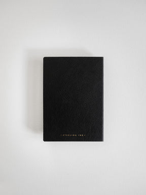 Matte black A6 grid notebook with a sophisticated faux leather cover, featuring minimal subtle branding for a premium, professional aesthetic.