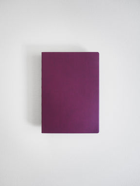 Solid deep mauve A6 notebook featuring a smooth, uniform cover, ideal for journaling, sketching, or detailed grid note-taking.