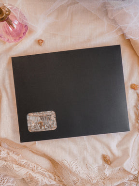 Matte black card featuring a detailed, vintage-style corner vignette illustration, perfect for a limited-edition December 2025 subscription kit.