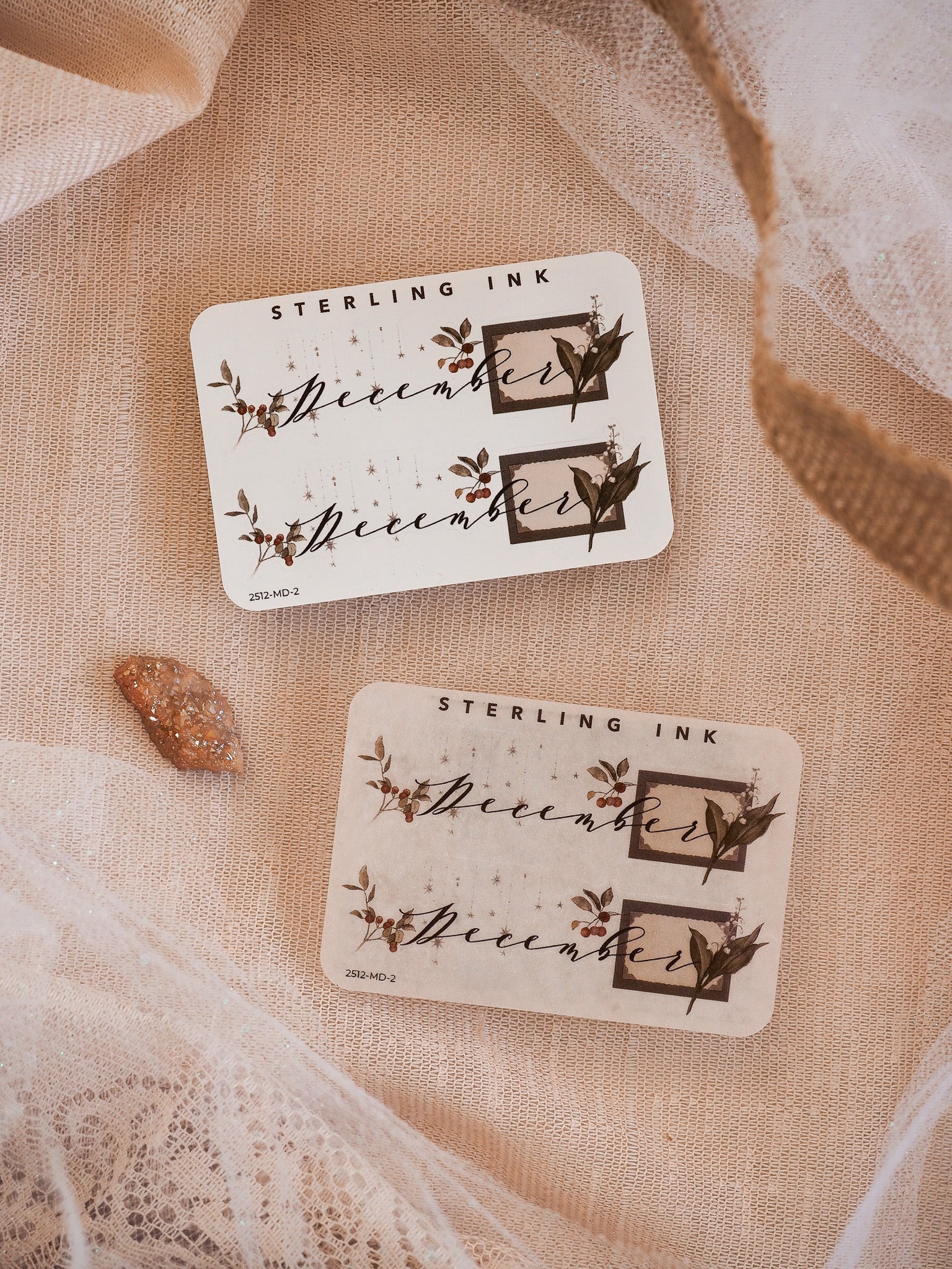 Decorative December month planner stickers featuring rustic typography and dark sepia ink renderings of woodland foliage and elegant winter accents.