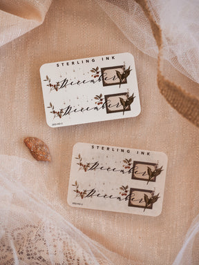 Decorative December month planner stickers featuring rustic typography and dark sepia ink renderings of woodland foliage and elegant winter accents.
