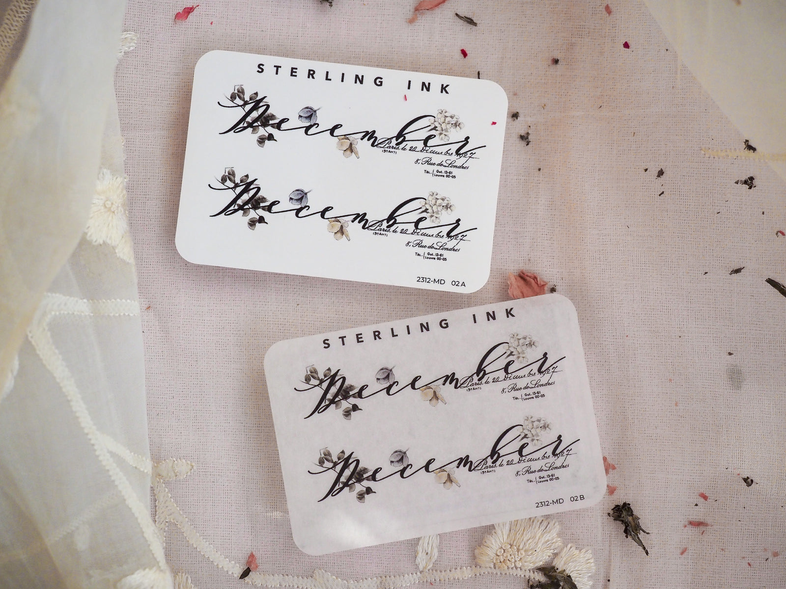 Elegant white stickers featuring "December" in ornate black calligraphy, beautifully decorated with delicate script and botanical floral motifs.