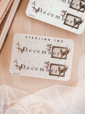 Elegant white sticker labels for December, featuring rustic botanical prints and coordinating berries framed in subtle sepia tones.