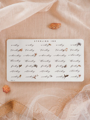 Cream-colored planner stickers marking the days of the week, featuring elegant black lettering and delicate watercolor floral accents for organizing schedules.