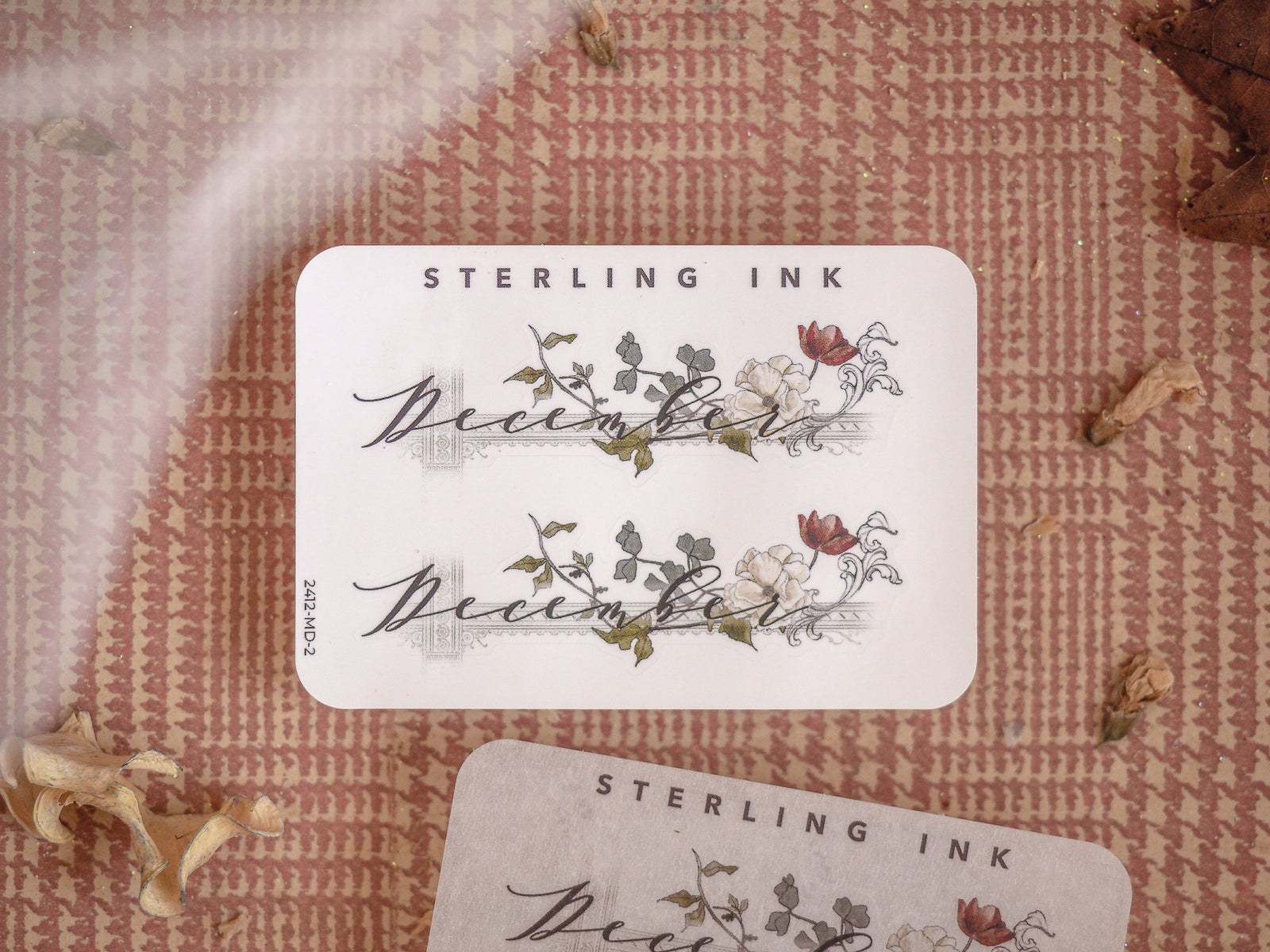 Elegant December month sticker featuring the word in scripted lettering and decorated with delicate watercolor illustrations of blooming flowers and green foliage.