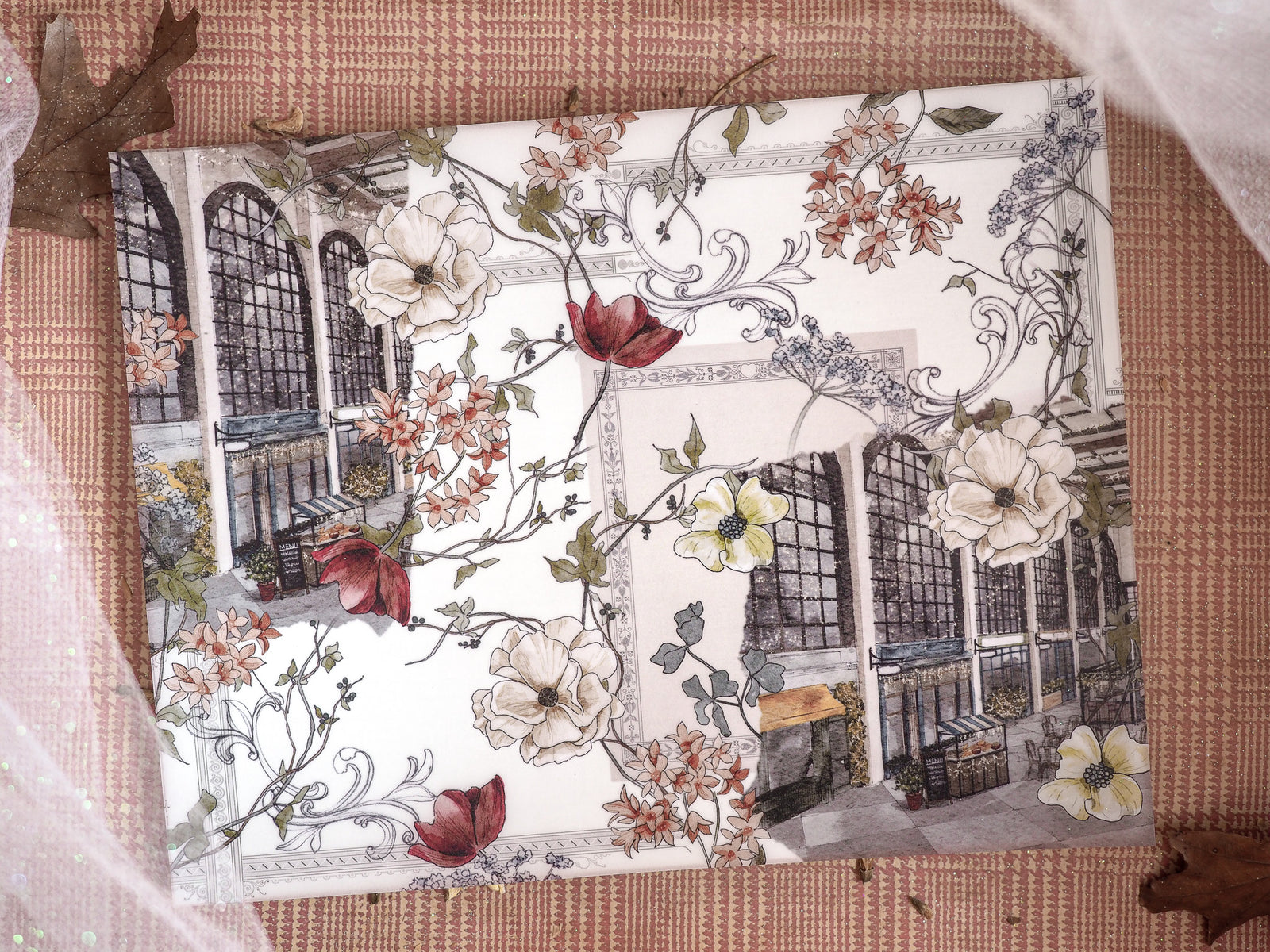 Ornate journal cover featuring a sepia-toned classical facade framed by abundant white, cream, and deep red winter floral vines for December 2024.
