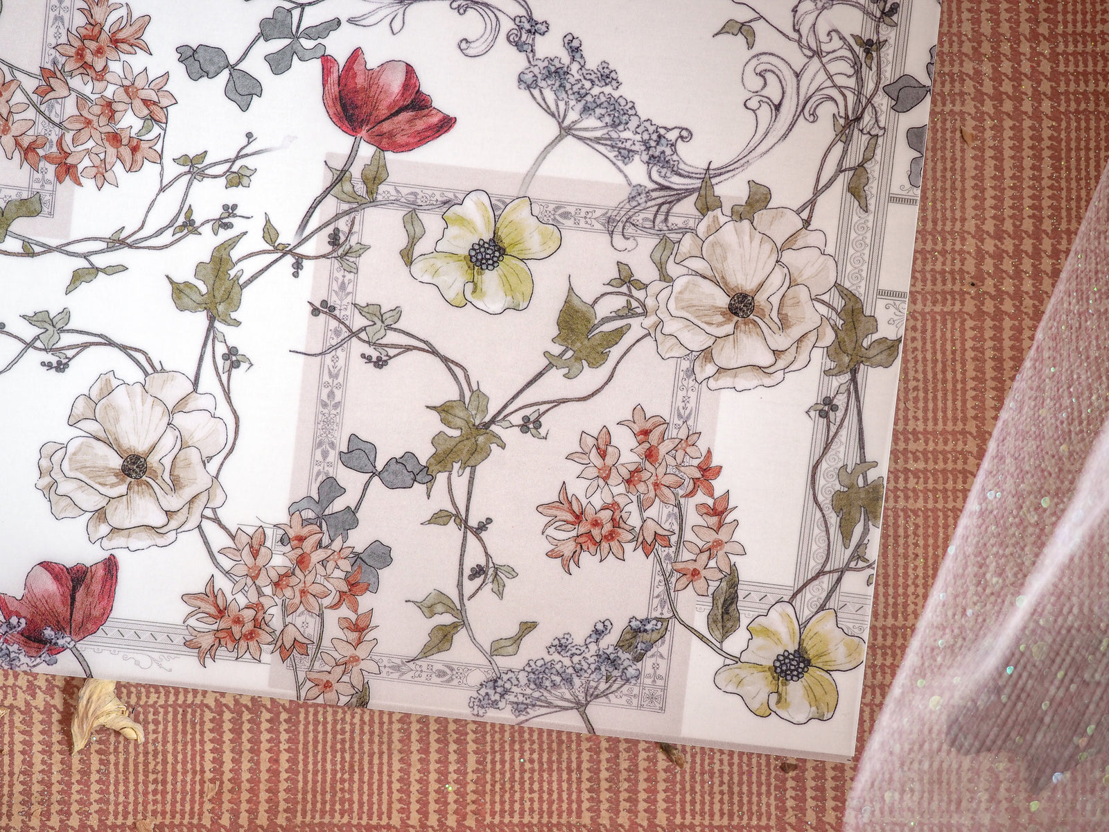 Elegant seasonal planner spread featuring a detailed botanical wreath pattern of autumnal flowers, cream blooms, and rich red accents on a pale background.