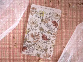 Botanical design sheet featuring a dense pattern of muted autumnal florals, creamy white blossoms, and rustic brown foliage against a delicate tan background.