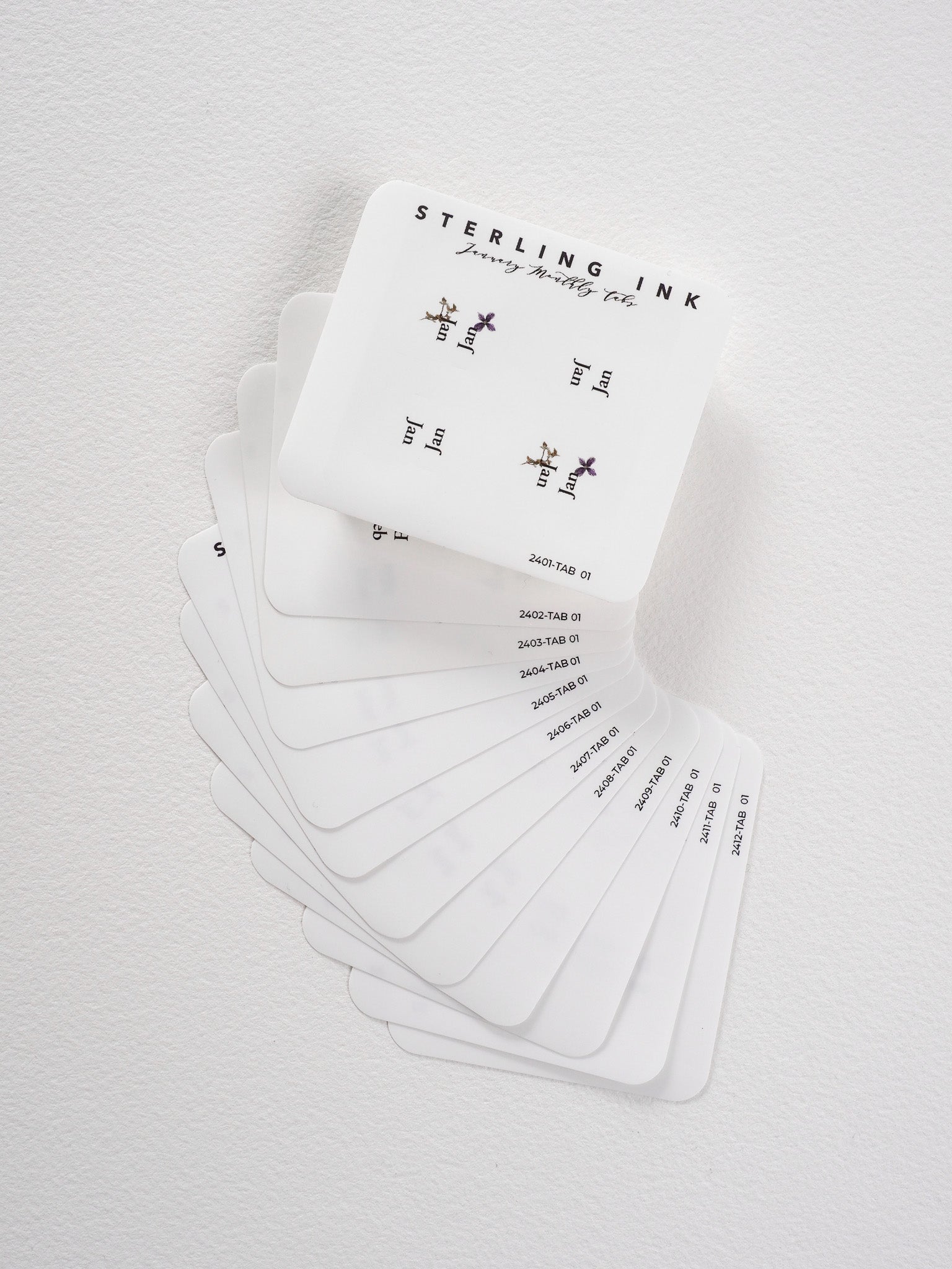 Minimalist set of white monthly tab stickers for 2024, featuring delicate floral accents and organized seasonal planning labels.