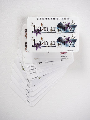 Beautiful watercolor monthly sticker set for journaling and planning, featuring elegant botanical floral designs and month names in deep purples and blues.