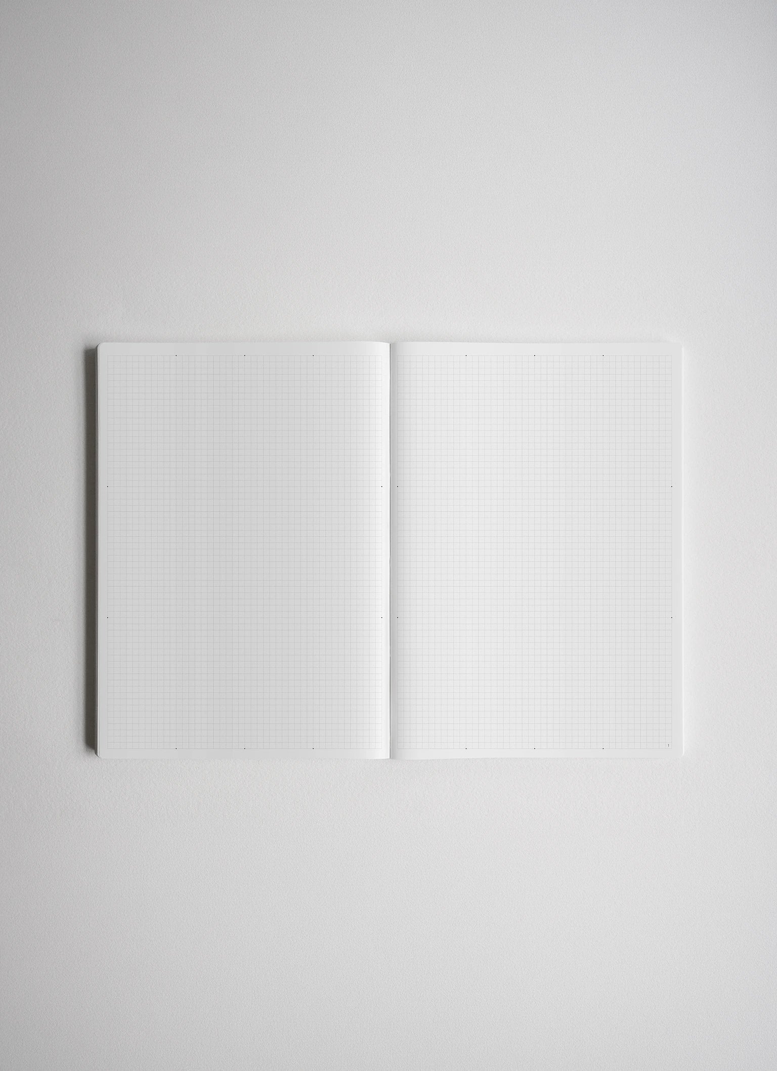 An open notebook with white graph paper pages, centered on a light gray background.
