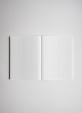 An open notebook with white graph paper pages, centered on a light gray background.