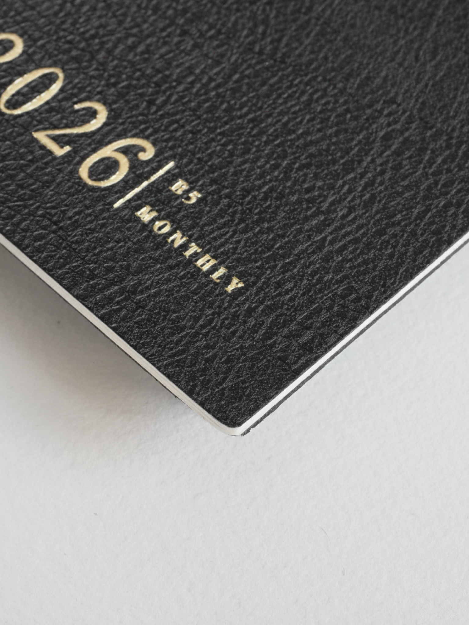 Dark grey B5 monthly booklet cover with elegant, embossed gold typography featuring the year "2026" and the word "MONTHLY."