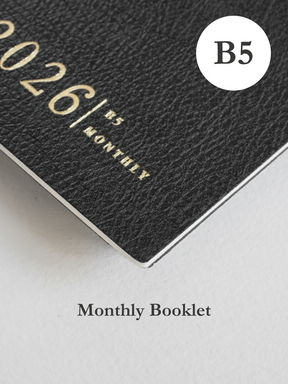 Minimalist dark charcoal B5 monthly planner booklet cover featuring the year 2026 and contemporary, elegant block typography.