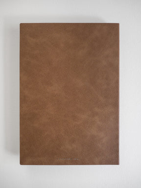 Minimalist B5 grid notebook bound in solid, textured earthy brown material, ideal for journaling and studying.