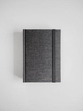 Textured charcoal gray B6 hardcover planner featuring a durable, minimalist design and elegant gold foil branding for a sophisticated look.