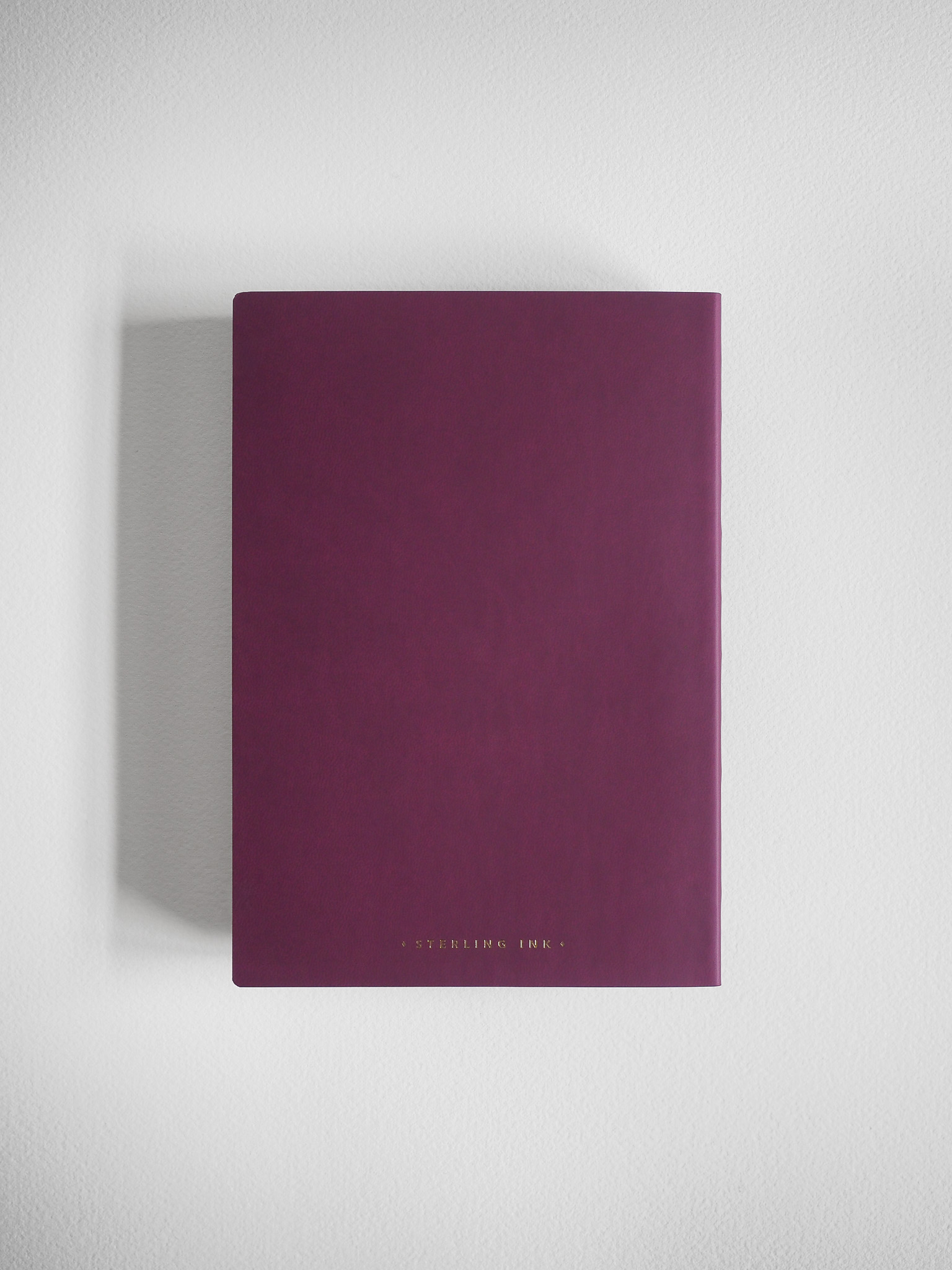 Deep maroon notebook with a matte cover and minimalist branding, ideal for writing, journaling, or tracking ideas.