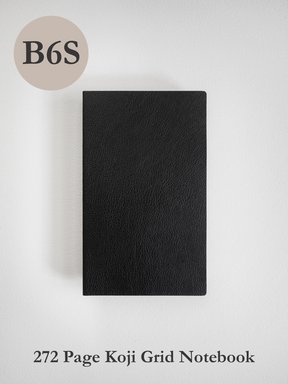 A sleek, solid black B6 grid notebook featuring a matte, minimalist cover, perfect for journaling and detailed academic notes.