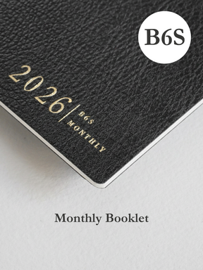 Dark slate monthly planner booklet with a textured cover, featuring elegant printed text reading "2026/B6S MONTHLY."