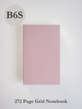 A solid, blush pink B6 mini notebook featuring a clean, minimalist cover ideal for writing, planning, or journaling on grid-ruled pages.