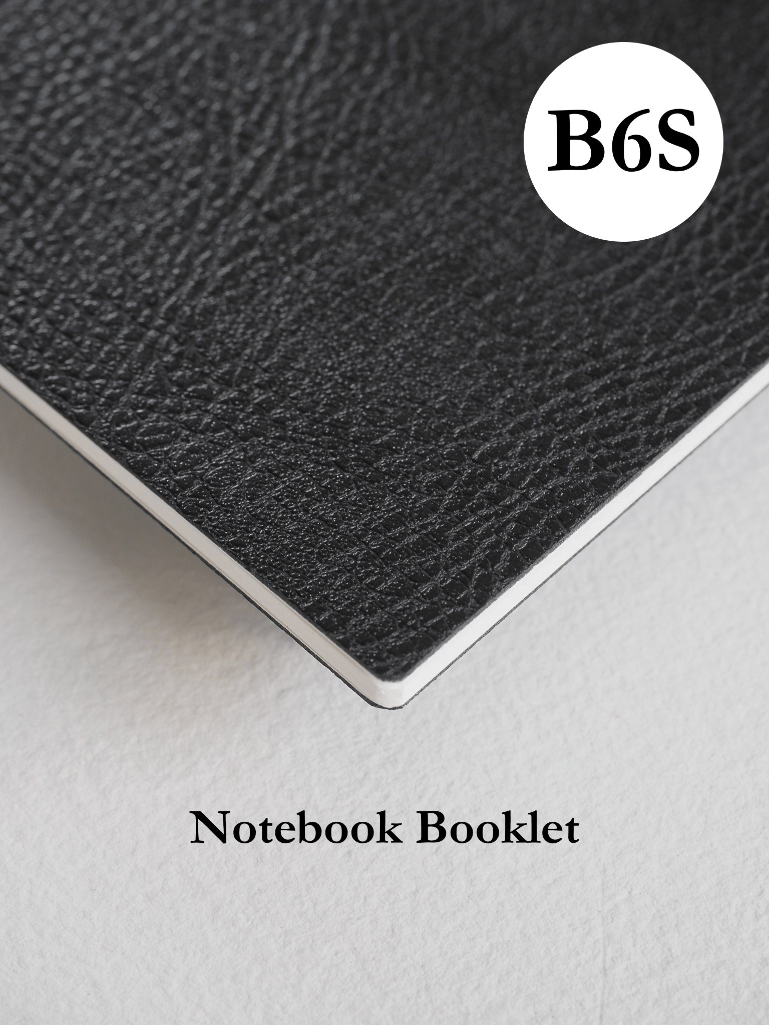 Matte black, slim B6 notebook booklet with a visible textured finish and a minimalist white branded logo centered on the cover.