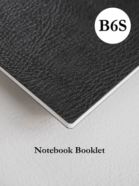 Matte black, slim B6 notebook booklet with a visible textured finish and a minimalist white branded logo centered on the cover.