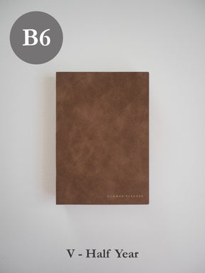 Minimalist B6 vertical planner featuring a rich, matte brown, textured cover stamped subtly with the "COMMON PLANNER" branding.