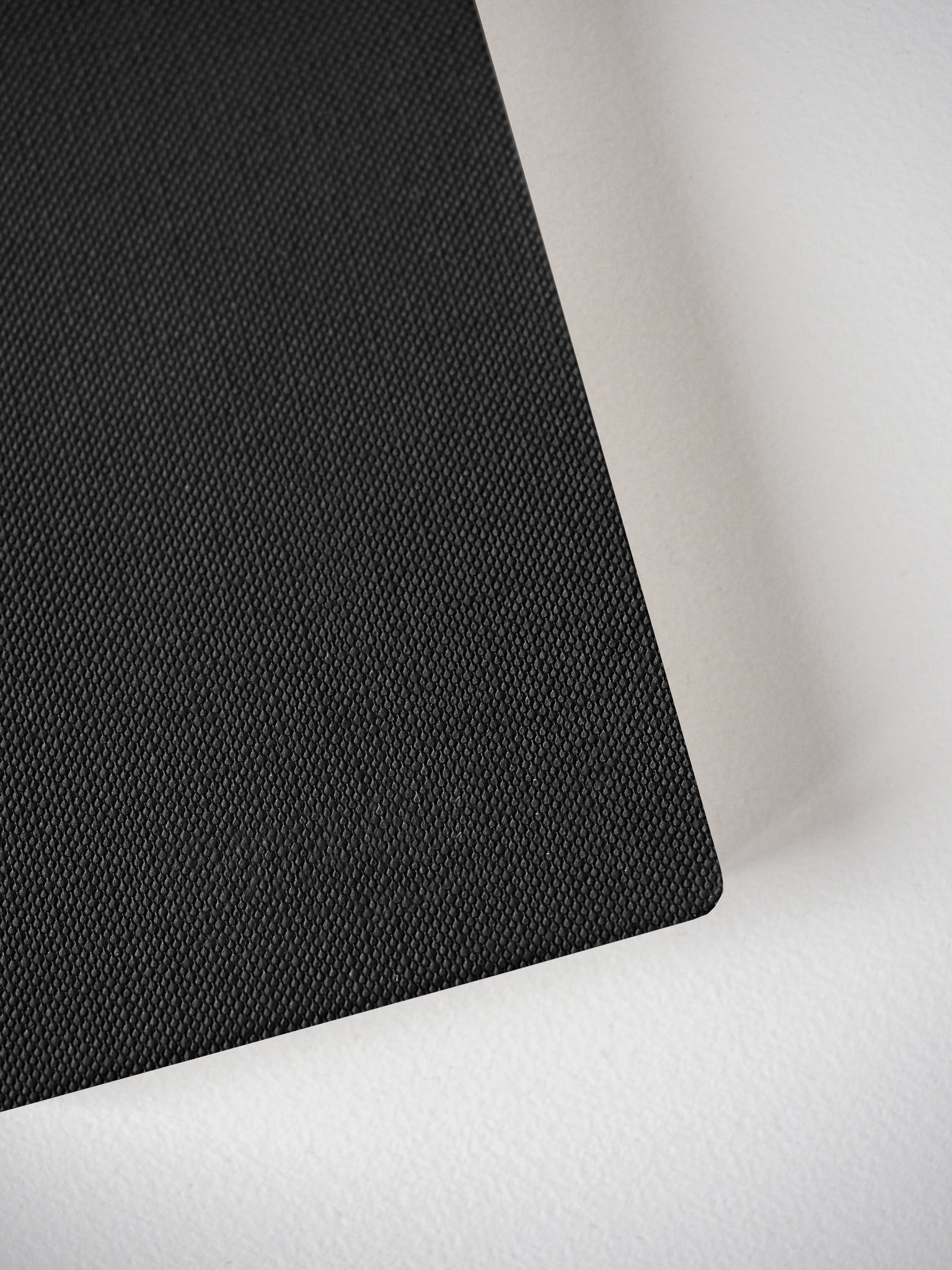Textured black passport notebook booklet, featuring a uniform cross-hatch design perfect for compact travel journaling and everyday notes.