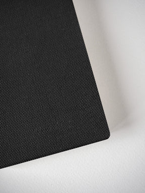 Textured black passport notebook booklet, featuring a uniform cross-hatch design perfect for compact travel journaling and everyday notes.