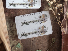Elegant January sticker featuring beautiful calligraphy, gold metallic floral accents, and lush green foliage on a cream background.