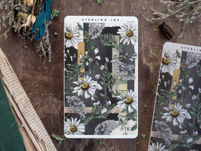 Botanical sticker strip for January 2025 featuring a vintage pattern of white daisies and lush dark green foliage on a black and cream background.