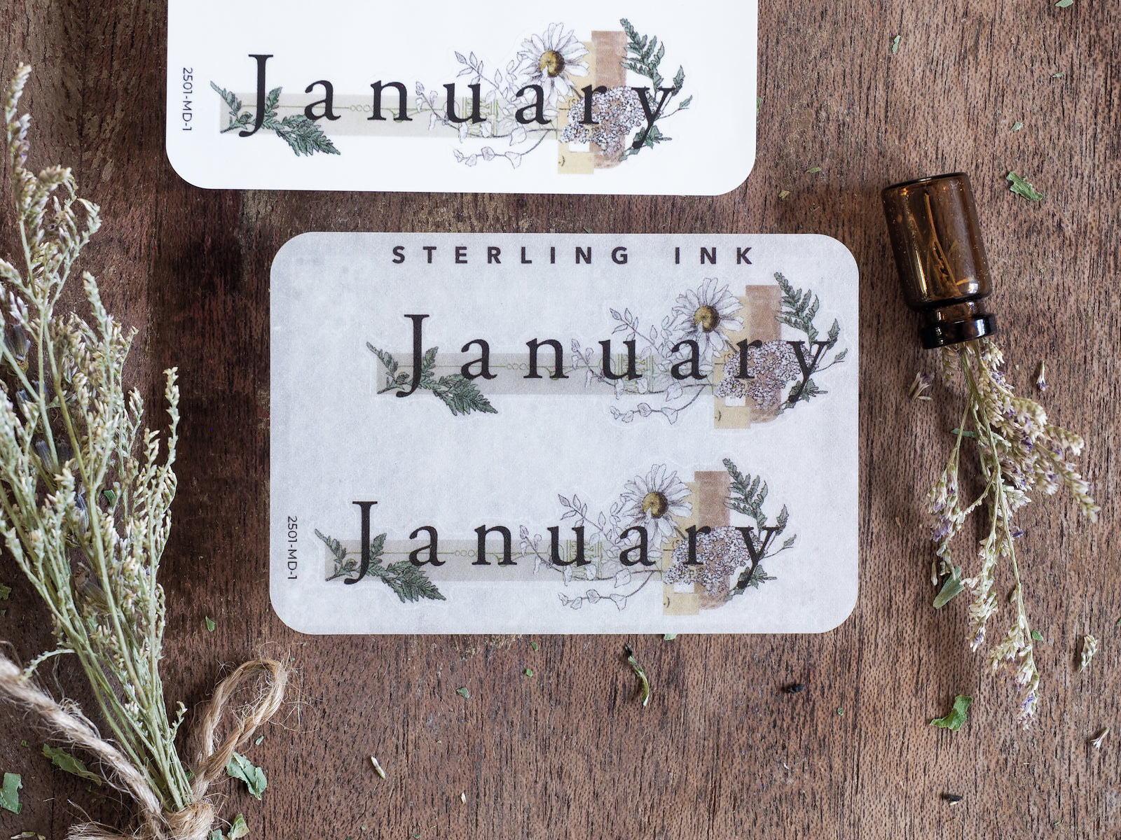 Rectangular planning stickers announcing "January," beautifully framed by muted, rustic botanical wreaths and delicate dried floral sprigs.
