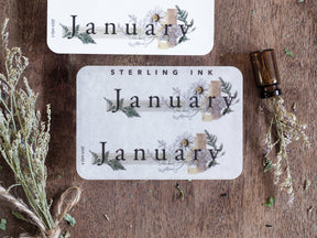 Rectangular planning stickers announcing "January," beautifully framed by muted, rustic botanical wreaths and delicate dried floral sprigs.