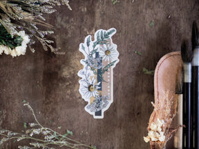Decorative vinyl die-cut sticker featuring a botanical wreath of white daisies and green foliage alongside a vertical calendar strip for planning or journaling.