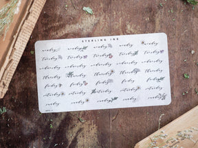Vintage "Sterling Ink" set of weekly labels featuring decorated days of the week (Monday through Sunday) on an off-white sticker sheet.