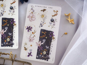 Botanical sticker arrangement set for January 2024, featuring watercolor depictions of purple, blue, and pink flowers on cream and deep navy backgrounds.