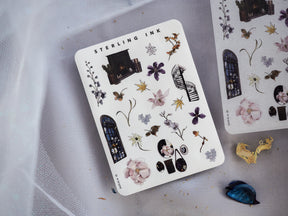 White sticker sheet featuring vintage botanical and architectural icons, including detailed flowers, gothic arched windows, insects, and various decorative elements from the "Sterling Ink" collection.