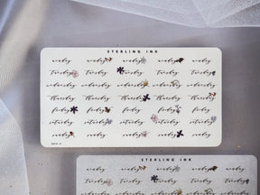 Decorative black-ink sticker sheet for journaling, featuring whimsical weekly labels for the days of the week and delicate floral accents.