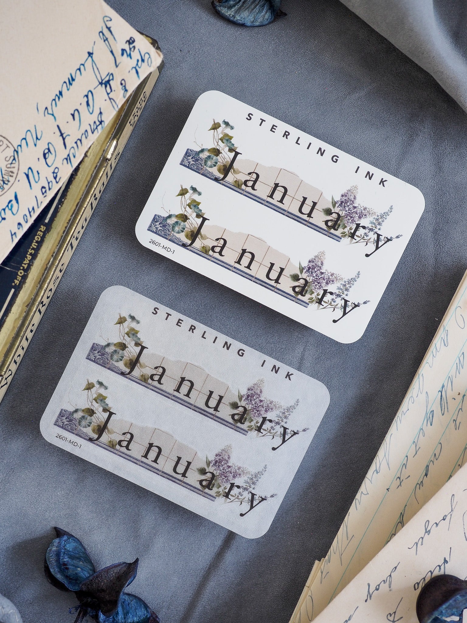 Elegant January month sticker featuring a botanical, watercolor wreath of delicate blue and green foliage around the name.