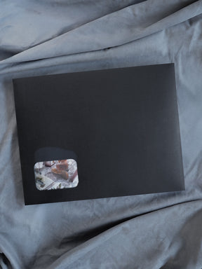 Sleek black planner kit featuring a small, contrasting corner patch adorned with muted, organic botanical prints and earthy tones.