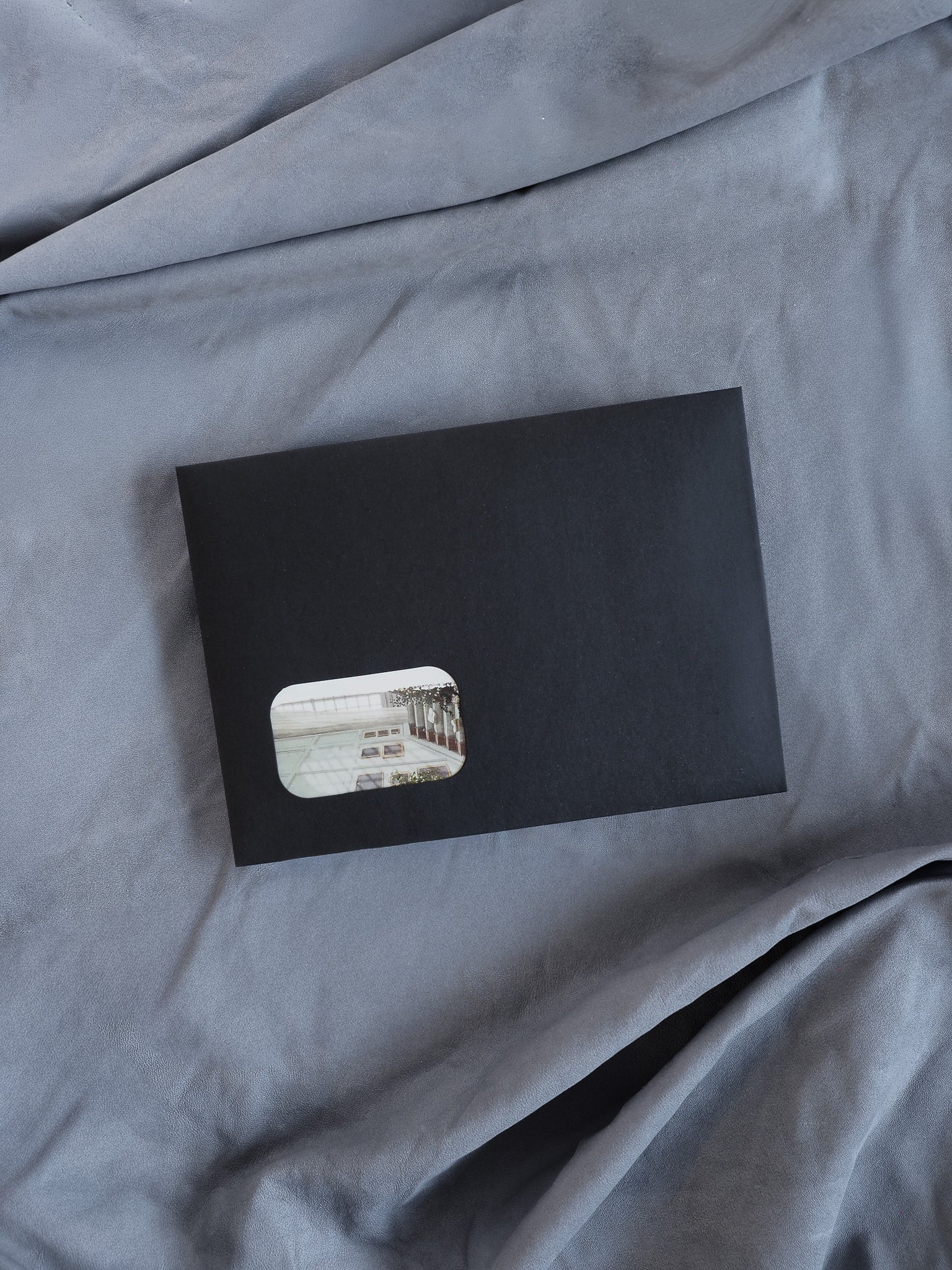 Matte black component featuring a recessed window that showcases a light-toned, classic architectural photograph, designed for a monthly subscription kit.