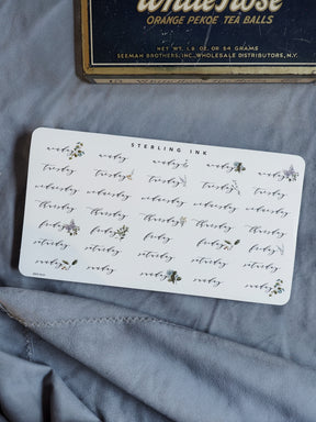Vintage-style sticker sheet labeling weekdays, decorated with small, detailed black ink floral clusters, perfect for journaling and calendar planning.