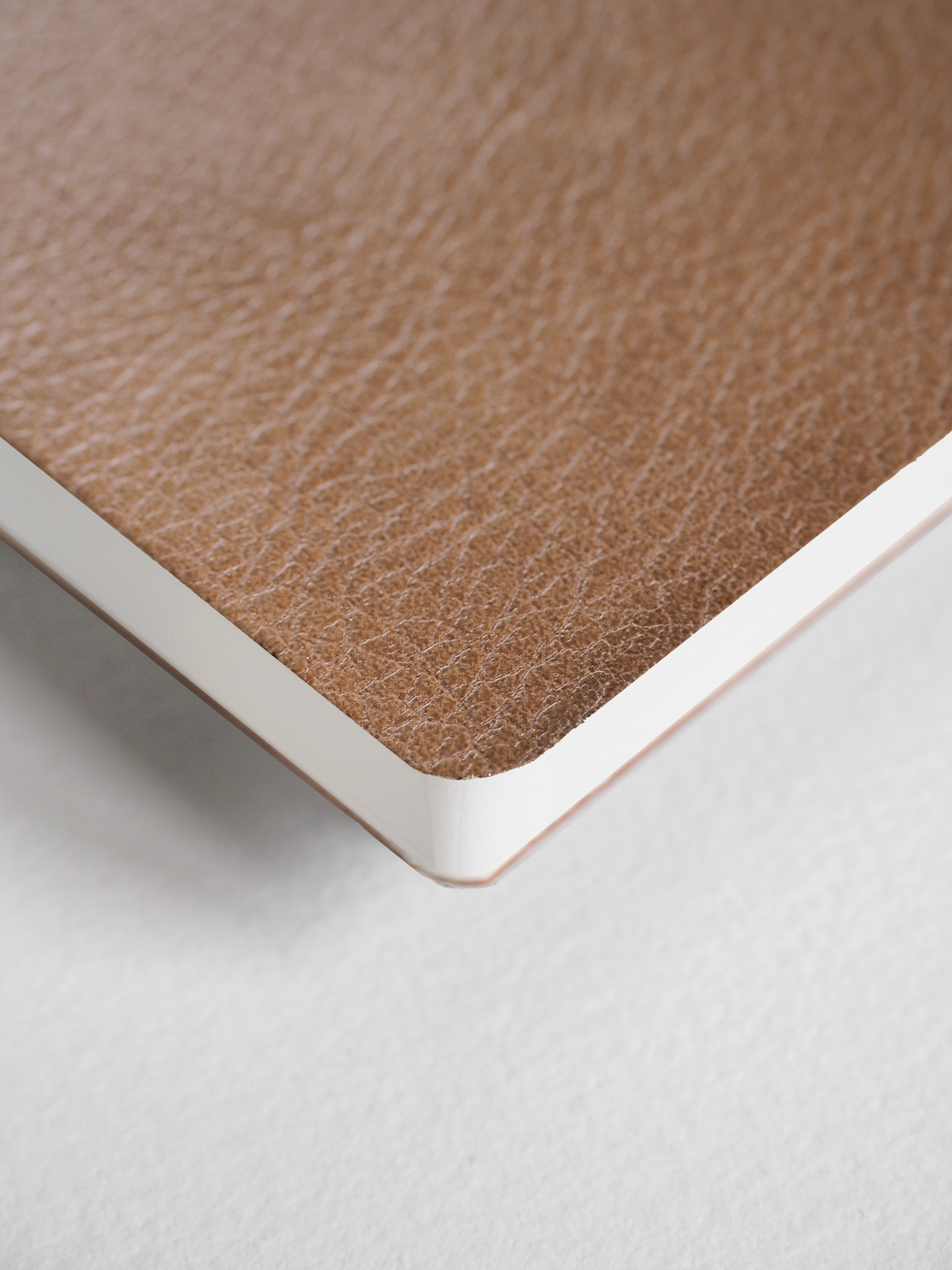 Textured, warm taupe notebook cover displaying a solid, earthy brown color and smooth binding edges.