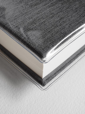 Textured charcoal gray notebook bound with a clear edge and featuring a sophisticated woven crosshatch pattern.