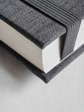 Elegant stack of two B6 hardcover diaries featuring textured dark gray woven fabric covers for organized, five-year undated planning.