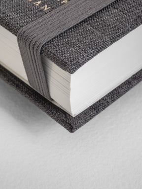 Close-up of a textured black book with white pages on a light gray background
#Color_Charocal