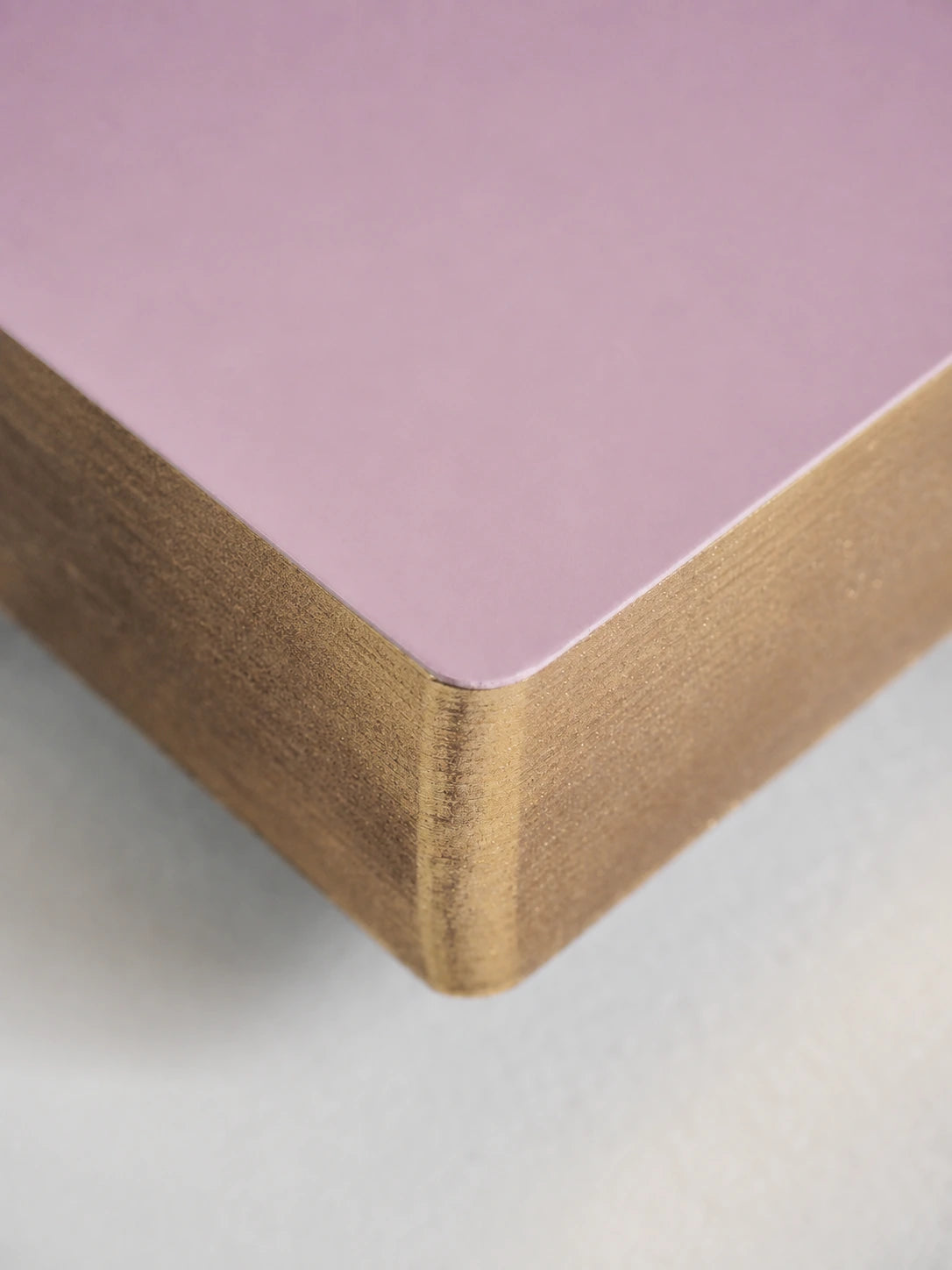 Close-up of a square product corner showing a matte light purple top surface and a natural wood grain side edge on a white background.
#Color_Fairyfloss