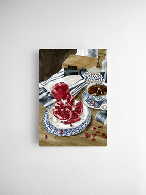 Vibrant watercolor illustration capturing a still life of fresh pomegranates displayed on a blue and white patterned saucer with coordinating teacups.